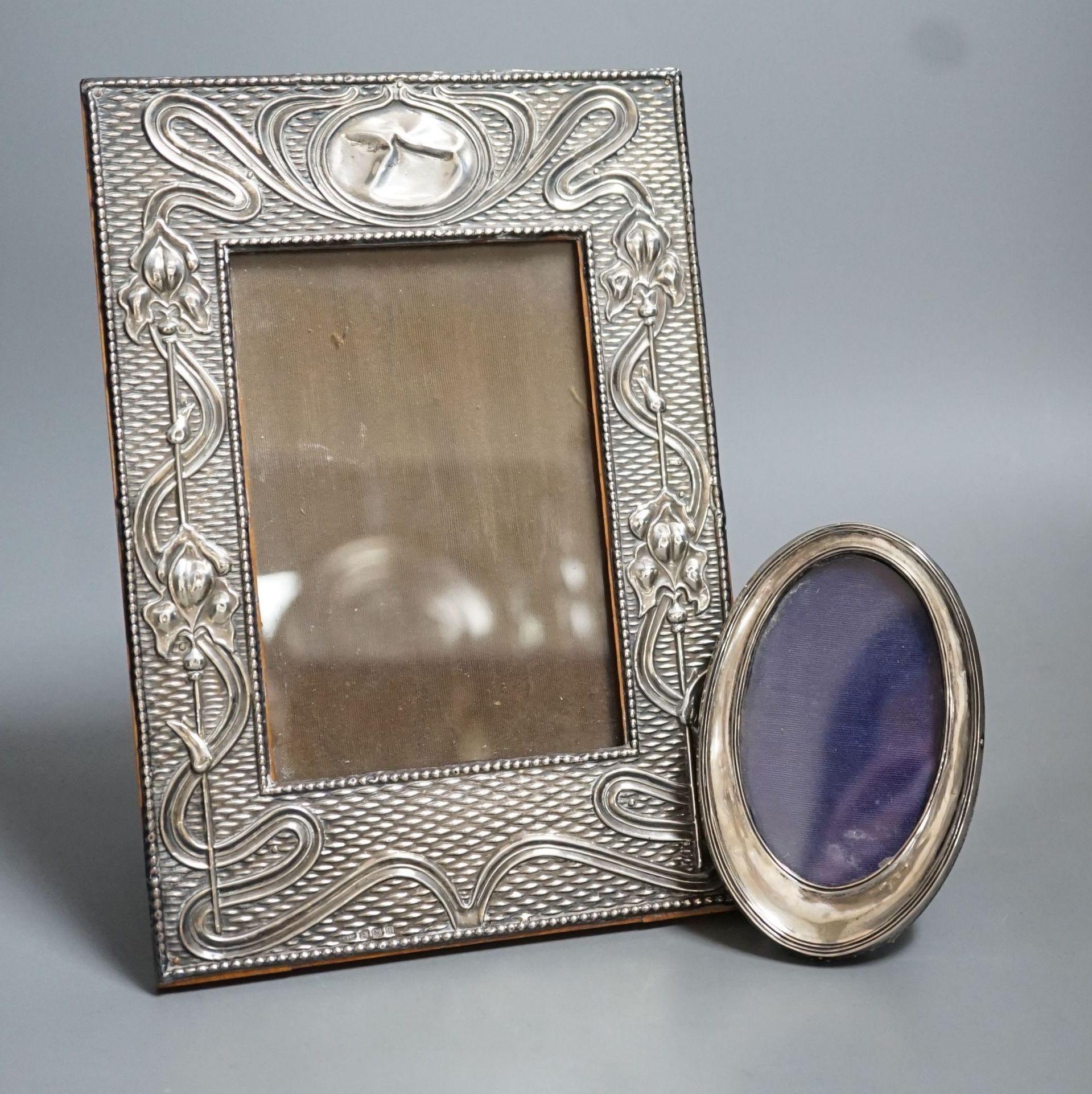 A George V Art Nouveau silver mounted photograph frame, Birmingham, 1912, 23.2cm and a smaller oval photograph frame.